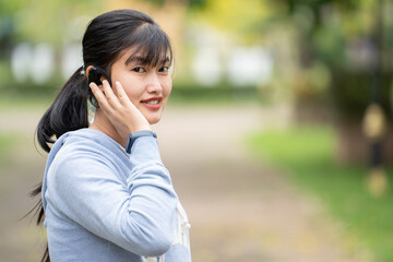 Attractive woman wearing wireless earphone before outdoor workout.Healthy lifestyle concept.