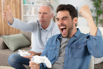 upset senior man losing video game to his mature son