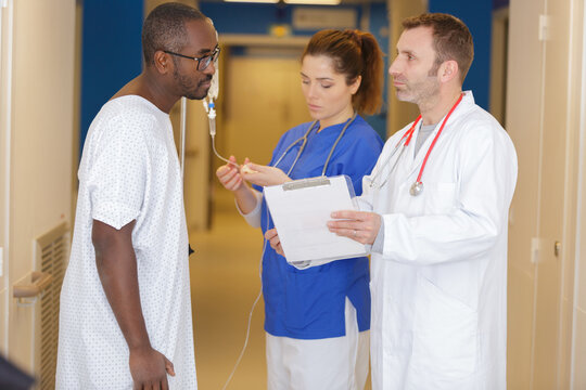doctor and patienet discussing over clipboard in hospital corridor