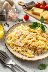 Pasta with ham in cream sauce in a ceramic plate on a light culinary background. Traditional Italian dish girandole in a bowl on the kitchen table