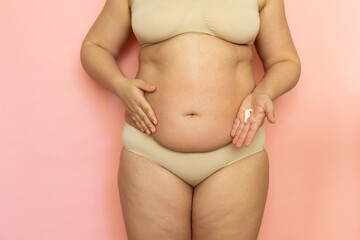 Fototapeta na wymiar Cropped overweight woman in underwear applying moisturizer cream lotion to her abdomen. Belly fat removal. Wearing underwear, doing self massage to puffy skin. Cellulite obesity. After childbirth.