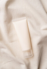 Top view Mockup facial skincare product white tube with blank label on farbic wavy background