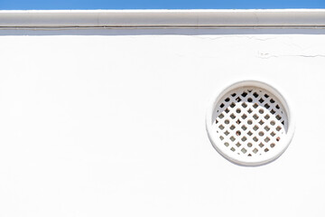 Minimalist Art Decorative circular window on a white wall and a small line of a blue sky.