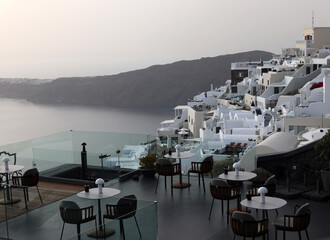 Tables on the restaurant terrace with a picturesque view of the sunset in Imerovigli. Santorini, Greece.