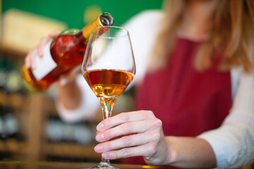 woman seller wearing apron pouring wine from bottle