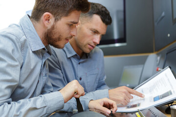 portrait of men looking at handbook