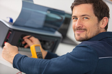 young male technician repairing digital photocopier