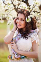 Portrait of a beautiful woman with long hair near flowering trees in spring.