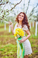 Portrait of a beautiful woman with long hair near flowering trees in spring.