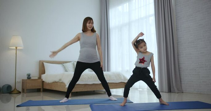 Asian mother and daughter  doing yoga together at home