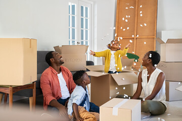 Happy african american family playing in new house with box filling material