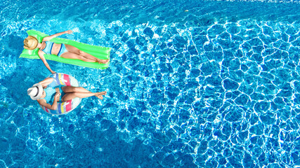 Children in swimming pool aerial drone view from above, happy kids swim on inflatable ring donut...