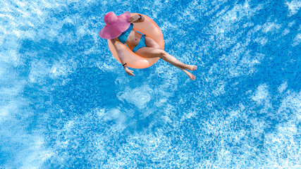 Beautiful woman in hat in swimming pool aerial top view from above, young girl in bikini relaxes...