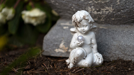 Fototapeta na wymiar Weißer sitzender Engel mit Perle in der Hand