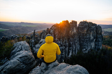 Man is squatting on the top of the mountain. Active recreation, climbing, trekking and hiking. Rocky towers. Beautiful moment the miracle of nature, during sunset or sunrise  - Powered by Adobe