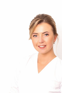 Close-up portrait of young smiling female caucasian healthcare worker standing staring at the camera on white background