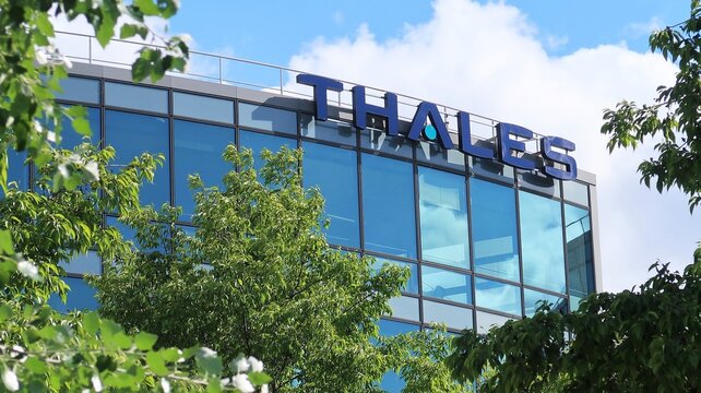 Enseigne / logo de l&rsquo;entreprise d&rsquo;&eacute;lectronique Thales, industrie fran&ccedil;aise de d&eacute;fense / a&eacute;ronautique / a&eacute;rospatial, sur la fa&ccedil;ade d'un immeuble de bureaux entour&eacute; d'arbres &agrave; Meudon &ndash; mai 2021 (France)