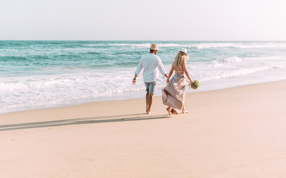 Junges Paar läuft den Strand entlang am Meer und ist total glücklich miteinander