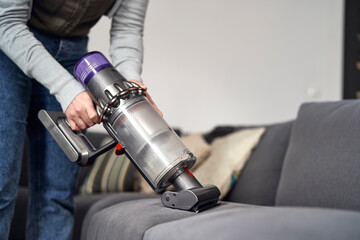 Close up of caucasian woman vacuuming sofa at home