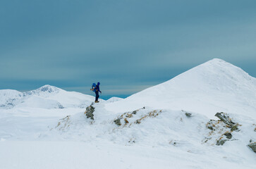 Fototapeta na wymiar Climber looking at majestic snowcapped mountain peak in winter landscape