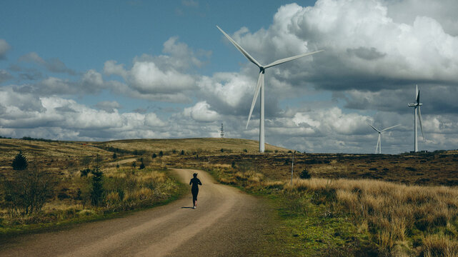 Woman running near wind turbine in the countryside