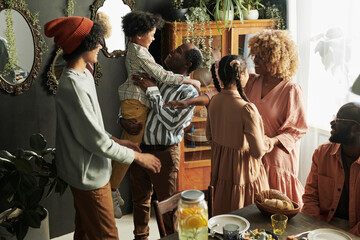 African big family embracing and talking to children during dinner at home