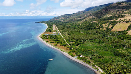 The aeroplane small landing strip, lush green landscape during wet season and perfect turquoise ocean with coral reefs on Atauro Island, Timor Leste