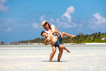 Mother carrying her son on a beah at summer