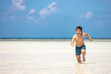 Little kid running on a white sand beach