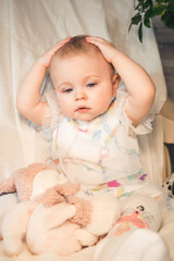 pensive one year old baby holding her head