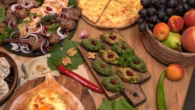  Close-up view of national georgian food on wooden table. Georgian cuisine. Georgian restaurant. khinkali, khachapuri, kebabs and pkhali. slide shot. High quality 4k footage