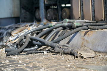 Burnt filling hoses and pistols lie on the ground after a gas station fire during the war.