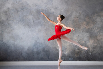 A cute little girl dreams of becoming a professional ballerina. A girl in a bright red tutu on pointe shoes dances in the hall. Vocational school student.