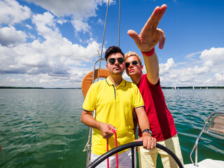young person point forward his hand to his friend the direction of sailing on sailing yacht. summer...