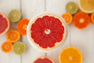 Fototapeta na wymiar cut colored citrus fruits on a white board table, orange, grapefruit, tangerine 