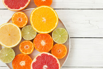 cut colored citrus fruits on a white board table, orange, grapefruit, tangerine
