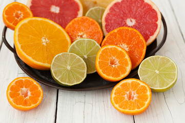 cut colored citrus fruits on a white board table, orange, grapefruit, tangerine
