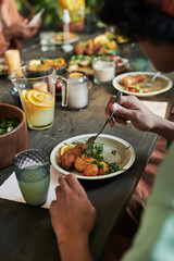 Close-up of teenage boy sitting at dining table and eating chicken with vegetables at holiday dinner