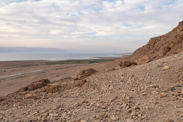 Fototapeta na wymiar View from a mountain near the Tamarim stream on the Israeli side of the Dead Sea at sunrise over the Dead Sea and over the mountains on the Jordan side near Jerusalem in Israel