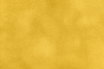 Background of yellow suede matte fabric closeup. Velvet matt texture of golden nubuck textile....