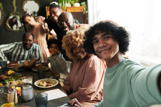 Teenage boy making selfie portrait of his big family during holiday dinner at table