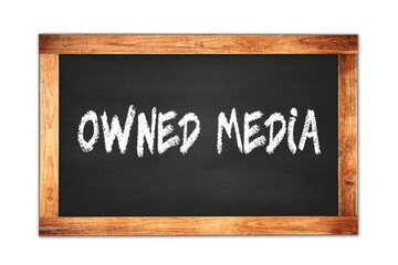 OWNED  MEDIA text written on wooden frame school blackboard.