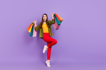 Full length body size view of attractive cheerful girl holding new things rejoicing isolated over violet purple color background