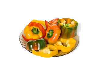 Sliced red, green and yellow paprikas on a glass plate. Horizontal composition on white background, minimal healthy nutrition concept
