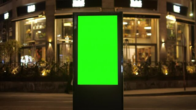 Billboard with a green screen on a background of city traffic in night time