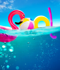 Pool text made of inflatable water toys underwater split photo