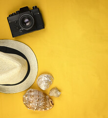 Yellow bright summer background with seashells, camera, straw hat and copy space. Concept, summer...