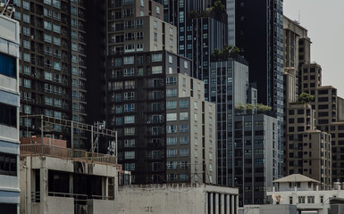 Fototapeta premium Architectural view of Overlapping city skyscrapers. Beautiful of Modern high-rise buildings with repeating structure glass and reflected. Angular geometric of building design, Selective focus.