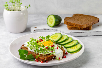 Sandwich with scrambled eggs, microgreens and pink pepper on a plate. Delicious and healthy snack
