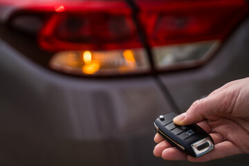 Person closes the car with a remote control key. Alarm system to protect the car. Close-up of the driver's hand